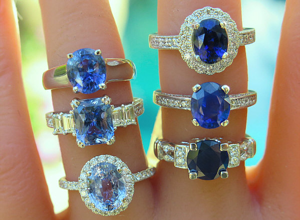 Blue sapphire engagement rings shown on hand, ranging from light cornflower blue to deep navy blue.
