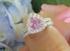 Natural trillion cut pink sapphire ring with a diamond halo in 14k white gold shown with it's matching diamond band in a natural setting held in the hand